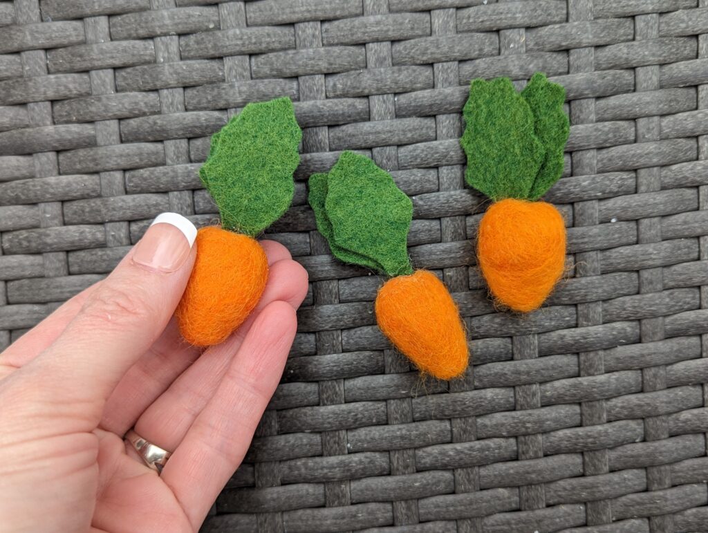 three wool felt carrots made of orange and green felt